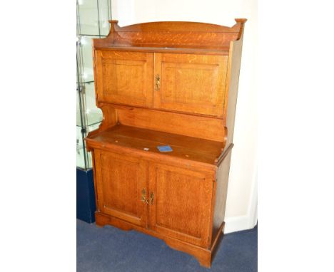 AN ART NOUVEAU GOLDEN OAK FOUR DOOR CABINET, the top section double doors revealing various shelving and smokers pipe holders