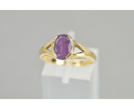 A 9CT GOLD AMETHYST RING, the oval amethyst within a part collet setting to the bifurcated shoulders, hallmark for London, ri