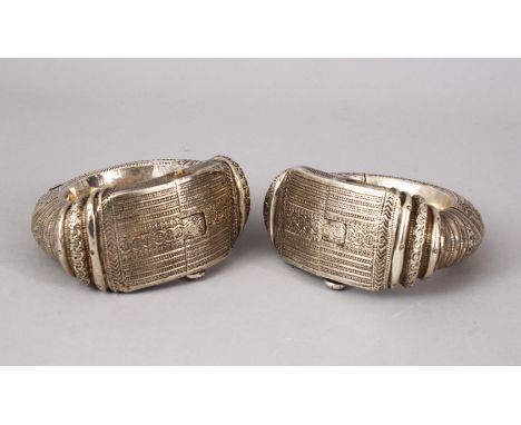 A GOOD PAIR OF ISLAMIC SILVER COATED LOCKING BANGLES, each carved decoration of hanging motifs, 11cm wide . 6.8cm internal.