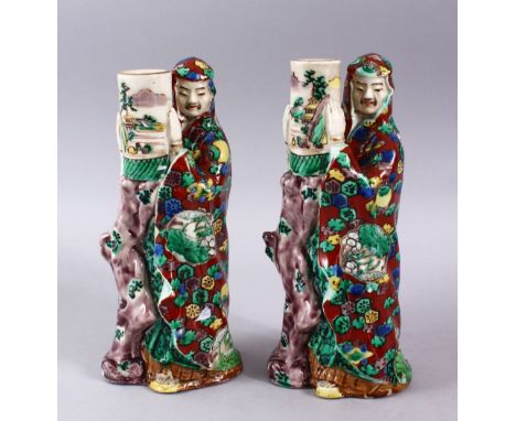 A PAIR OF JAPANESE MEIJI PERIOD KUTANI PORCELAIN CANDLE STICK FIGURES, in the form of two figures holding landscape decorated