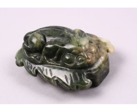 A CHINESE CARVED JADE BELT BUCKLE / DECORATION OF A RECUMBENT KYLIN, upon a leaf, 6.5cm.