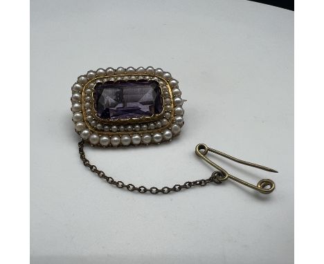 An antique 9ct gold amethyst and seed pearl brooch,
unhallmarked,
25mm x 18mm,
fitted with a safety chain,
6.9 grams in weigh