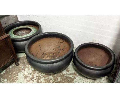 GARDEN POTS, a collection of four, black finish, with one in a glazed green ceramic, 57cm diam at largest. (4) 