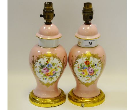 A pair of baluster shaped lamp bases painted with floral motif on a pink ground