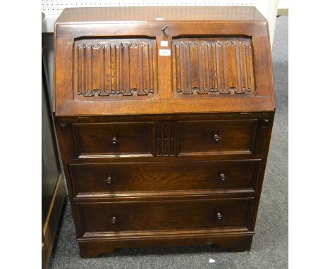 An early 20th Century oak bureau, fall front carved linen fold door, enclosing tooled leather inlaid writing surface, pigeon 