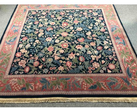 A hand woven carpet with a William Morris flowerhead design across the field within a complementary salmon border. L.255 W.24