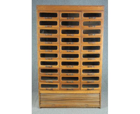 A mid century vintage draper's shop cabinet, full height with a bank of thirty glazed drawers. H.193 W.119 D.50cm. (Tambour s