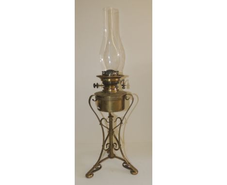 A decorative oil lamp with brass reservoir and on brass tripod base, 42cms high not including chimney