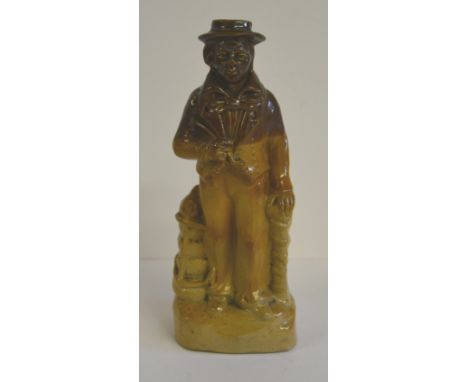 A 19th Century saltglaze stoneware figural whisky flask in the form of a seaman holding a pipe and standing beside an anchor,