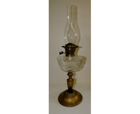A late 19th/early 20th Century oil lamp with star cut clear glass reservoir on brass pedestal and circular brass foot, height