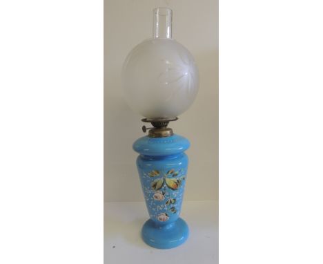 A late 19th/early 20th Century oil lamp with light blue glass reservoir fitting onto matching glass pedestal base painted wit