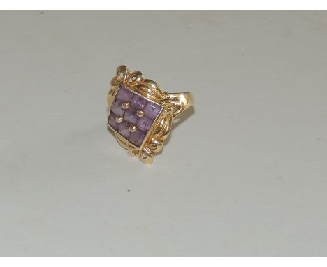 A 14 k gold, ladies dress ring, set with a central panel of nine square cut amethysts, with swag and bow decoration. Ring siz