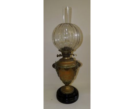 A Victorian oil lamp with etched glass shade and urn shaped brass base with applied scrolling brass handles on stepped black 