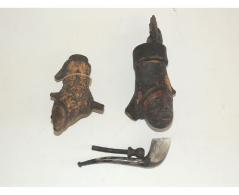 Two primitive carved wood pipe bowls, each worked with human and animal masks, one with original oak leaf and acorn stopper, 