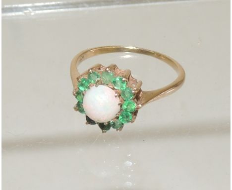 A ladies 9ct gold dress ring, set with a central Cabouchon opal, with a surround of green stones. Ring size Q +. 