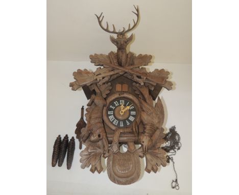 A late 20th Century black forest style cuckoo clock, the case with applied carved wood, dead rabbit, gamebird, hunting horn a
