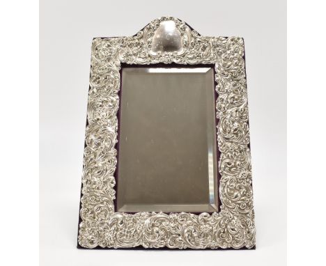A Walker &amp; Hall silver fronted mirror with an easel back. The mirror having bevelled glass within a repousse silver frame