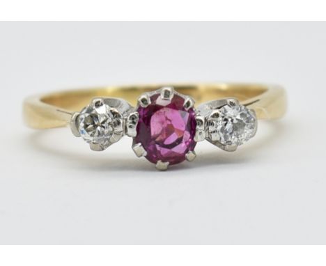 A 15ct gold ruby and diamond three stone ring. The ring set with a central oval cut ruby flanked by two old cut diamonds. Est