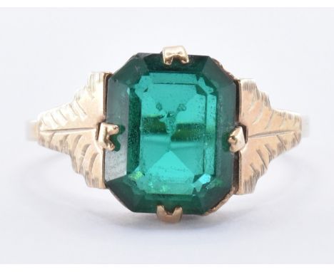 A 9ct gold ring being set with a green paste stone in an emerald cut. The ring having engraved shoulders. Marked 9ct. Weight 