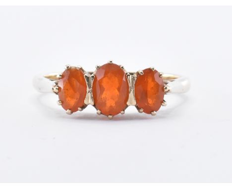 A 9ct gold unmarked three stone ring. The ring set with three fire opal cabochon stones. Central stone measures 7mm x 4mm. Ri