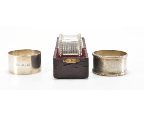 A group of three early 20th Century silver hallmarked napkin rings to include one having striped decoration and gadrooned bor
