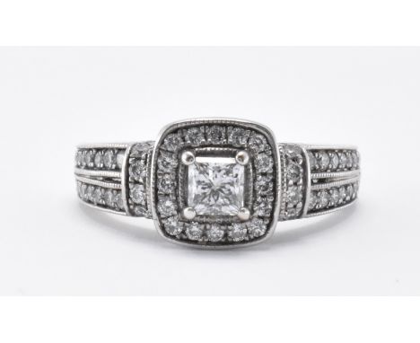 A 14ct white gold and diamond ring having a square head set with a central princess cut diamond and a halo of diamonds surrou