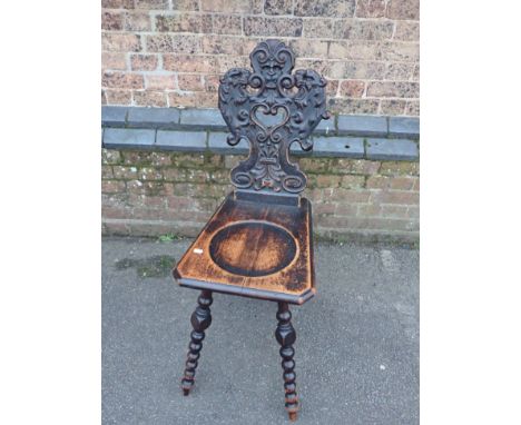 A 19TH CENTURY STAINED PINE HALL CHAIR with Renaissance inspired grotesque carved back, dished seat and bobbin-turned legs