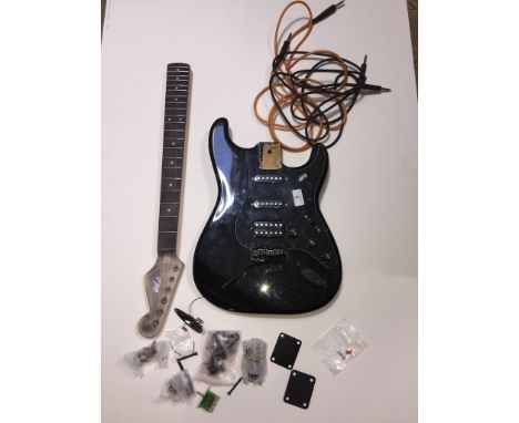 A black electric guitar in pieces. Stratocaster shape, pickguard has pots and pickups attached - serial numbers indicate Squi