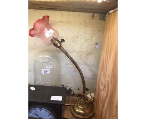 An early 20th century copper and brass angle lamp with cranberry glass shade. 