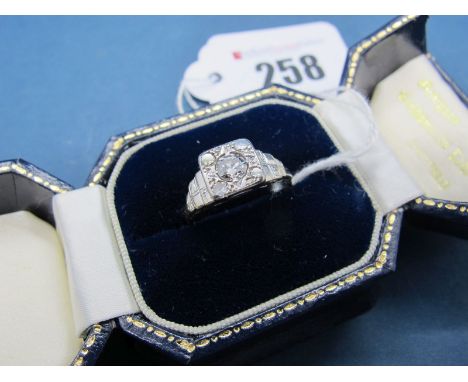 An Art Deco Diamond Set Ring, the high square panel set with graduated old and single cut stones, between textured stepped sh