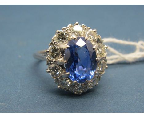 A Large Sapphire and Diamond Cluster Ring, the central (9mm) oval sapphire claw set, within claw set border of ten brilliant 