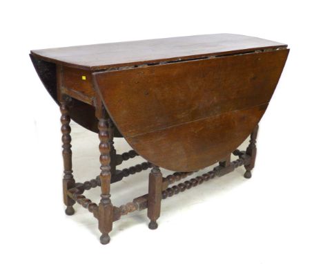 A 17th century oak drop leaf table, with circular top raised on eight bobbin turned legs, double gate leg action, 120 by 44 b