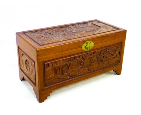 A 20th century Oriental camphor wood chest, decorated with relief carved panels, featuring a sliding tray to its interior, ra