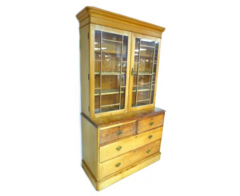 A Victorian pine bookcase, twin glazed doors, enclosing three shelves, below two drawers over twin doors enclosing shelf, wit