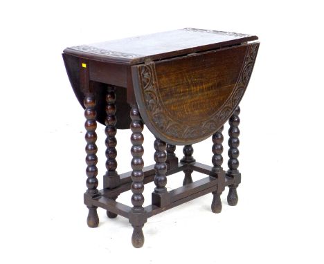 A Victorian oak drop leaf table, the oval surface with carved lunette border to the edge, gate leg action, bobbin turned supp