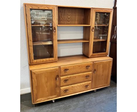 AN ERCOL GOLDEN DAWN DRESSER  the upper sectino with pair of glazed doors enclosing shelves, base with three drawers flanked 