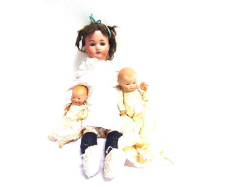 A GERMAN BISQUE SOCKET HEAD DOLL  with a brown cropped wig, sleeping blue-grey glass eyes, and an open mouth with four upper 