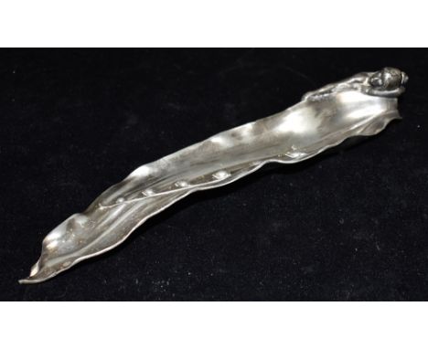 AN ART NOUVEAU WMF SILVERPLATED PEWTER PEN TRAY  in the form of a nude female seated beside a lily of the valley leaf, model 