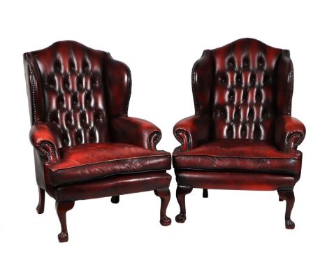 A pair of Georgian style button backed leather wingback armchairs.