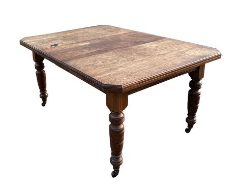 A late 19th century walnut extending dining table with one extra leaf, the rectangular top with canted corners, on ring turne