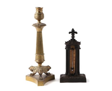 A Victorian cast iron desk thermometer, 21cms high; together with a Regency brass candlestick on tripod lion paw feet (2).