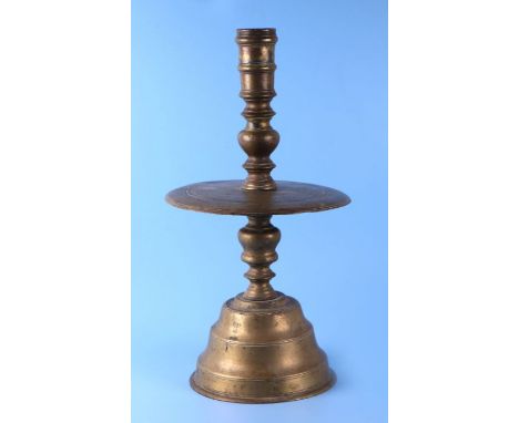 A 17th / 18th century Dutch bell bottom candlestick with ring turned column above a large circular pan, on a stepped conical 