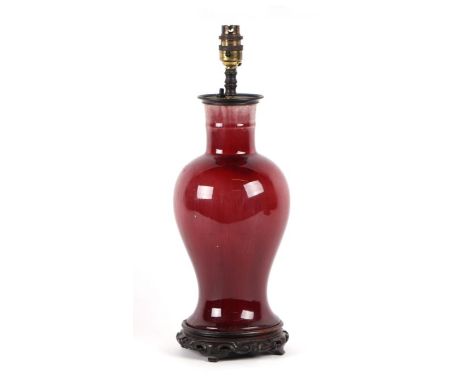 A Chinese sang de boeuf baluster vase converted to a table lamp on a carved hardwood stand, 33cms high excluding fitment but 