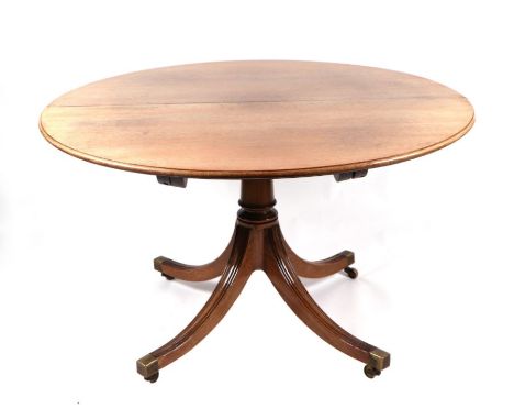 A George III style mahogany circular tripod dining table inset with one extra leaf, on a turned column with quatrefoil base, 