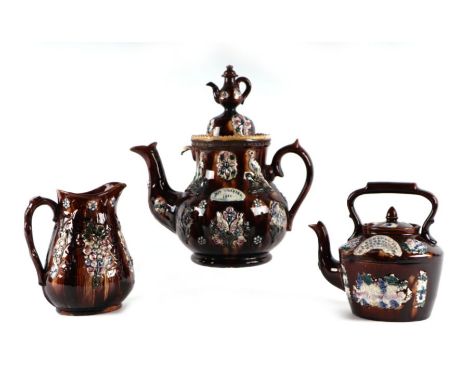 A Barge ware pottery teapot with plaque to 'Mrs Chappel 1891', 36cms high; together with a similar teapot and jug (3).Conditi