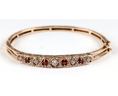 A 9ct gold hinged bangle set with white and red stones, 15.6g.