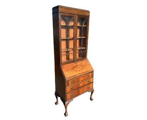 A 1930's walnut bureau bookcase, the upper section with a caddy top above two astragal glazed doors enclosing a shelved inter