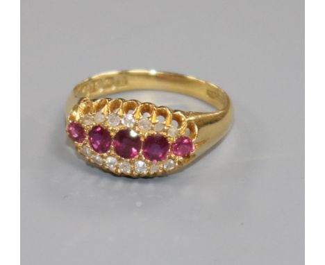 An early 20th century 18ct gold, five stone ruby elliptical shaped ring with diamond set border, size O.