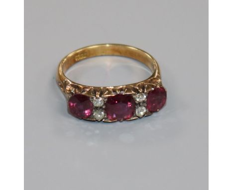 An early 20th century 18ct gold, three stone ruby and four stone diamond ring, size L.