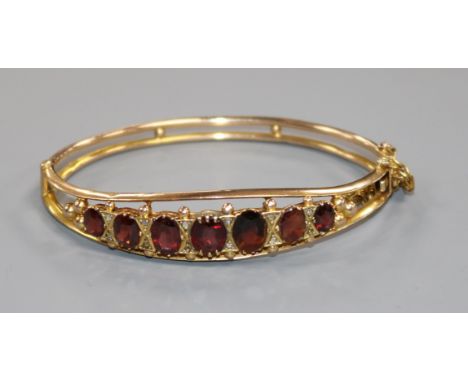 A 9ct gold and garnet set hinged bangle.